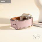 A pink leather watch band with a silver watch face. The band has a stitched design and a buckle closure.