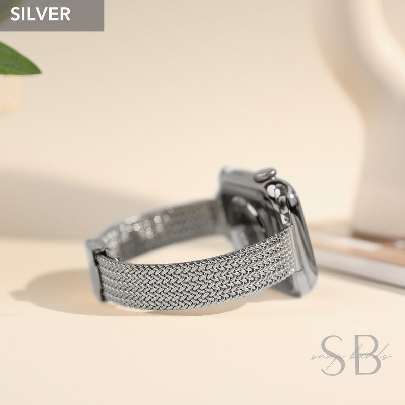 A silver-colored smartwatch with a woven metal band. The watch is displayed on a light-colored surface, with the word "SILVER" in a gray box in the upper left corner.
