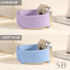 Two Apple Watch bands with a floral design. The band on top is lavender and the band on the bottom is light blue.