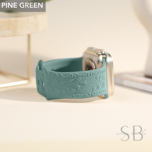 A light blue silicone Apple Watch band with a floral design. The band is embossed with a delicate vine pattern and has a smooth finish.