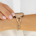 A rose gold Apple Watch band with a twisted design and clear crystal accents. The band is made of metal and has a snap closure.