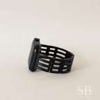 A black smartwatch with a woven band. The watch face is rectangular and the band has a unique, open design. The watch is set against a neutral background, highlighting its sleek, modern aesthetic.