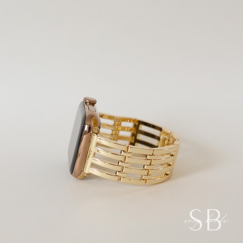 A gold-toned Apple Watch with a matching gold band. The band features a woven design with rectangular links. The watch face is dark, and the overall aesthetic is elegant and modern.