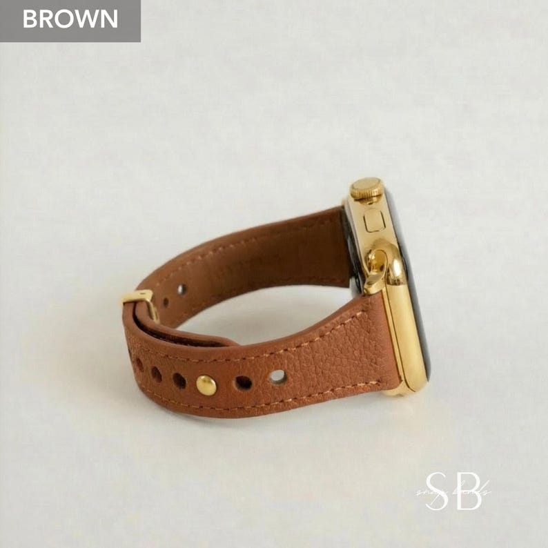 A brown leather watch band with a gold-colored watch face. The band has a series of small, gold-colored rivets. The watch face is rectangular with rounded corners. The word "BROWN" is in a gray box in the upper left corner.