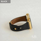A black leather watch band with gold-colored hardware. The watch face is gold and the band is secured with gold-colored rivets. The word "BLACK" is in a gray box in the upper left corner.