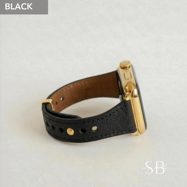 A black leather watch band with gold-colored hardware. The watch face is gold and the band is secured with gold-colored rivets. The word "BLACK" is in a gray box in the upper left corner.