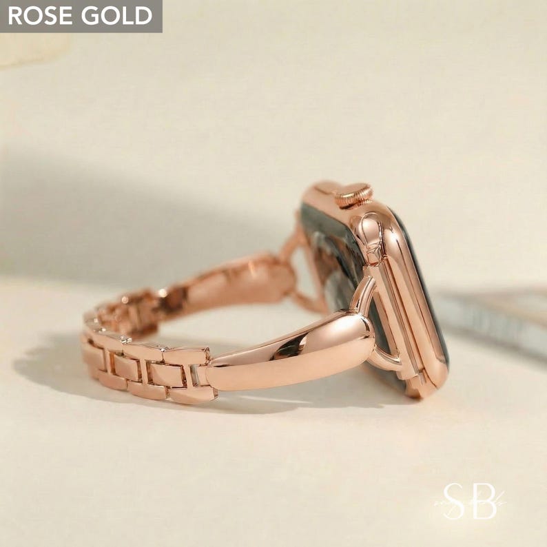 Rose gold smartwatch with a matching link band. The watch face is black, and the band is made of small, rectangular links. The watch is angled, showing the side and the band's connection to the watch face. The text "ROSE GOLD" is in the top left corner.